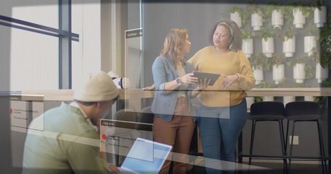 Colleagues collaborating over tablet in modern coworking lounge with natural light