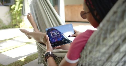 Young Woman Relaxing on Hammock Watching Show on Tablet
