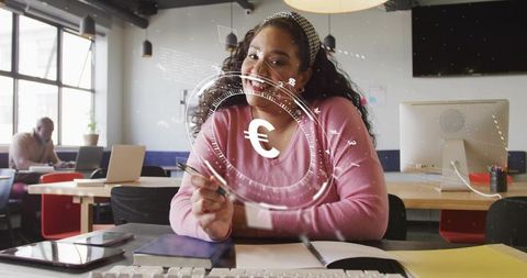 Smiling mid-adult african american woman writing in coworking space with digital euro hologram
