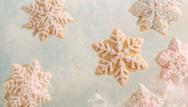 Pastel snowflake sugar cookies with royal icing and gold confetti flatlay