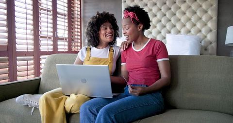 Diverse female couple shopping online with laptop and credit card