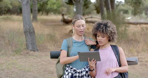 Two Young Women Hiking with Tablet in Forest Discussing Destination