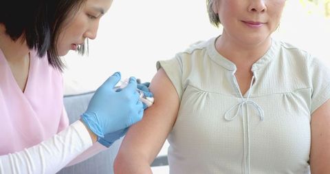 Home vaccination of senior asian woman by healthcare worker