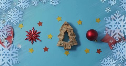 Displaying cork christmas tree ornament on blue background with red bauble and snowflakes