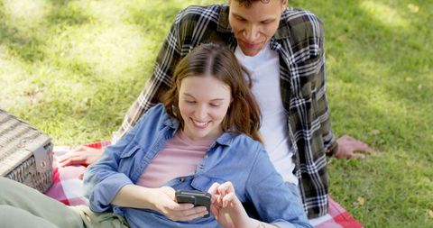 Happy Couple Enjoying Picnic with Smartphone in Sunny Garden - Download Free Stock Images Pikwizard.com