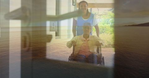 Nurse Assisting Senior Patient in Wheelchair with Ocean View Behind