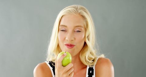 Playful woman with green apple embracing healthy lifestyle
