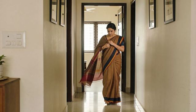 Graceful woman walking and adjusting sari pallu in glossy tiled home corridor