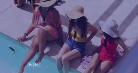 Three women relaxing by poolside in sun hats during summer