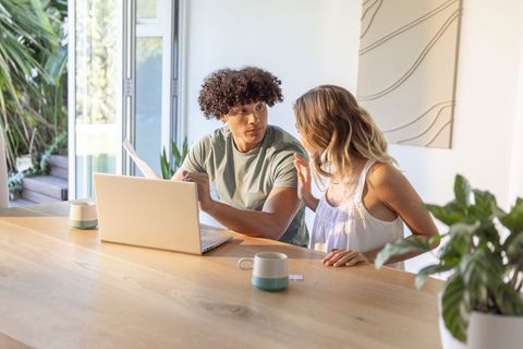 Young couple reviewing finances on laptop at bright modern kitchen table
