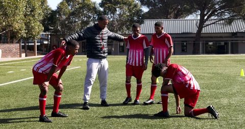 Coach Supporting Tired Young Soccer Players on Field