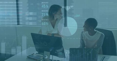 Collaborating on digital analytics: Two women analyzing data and charts in modern office