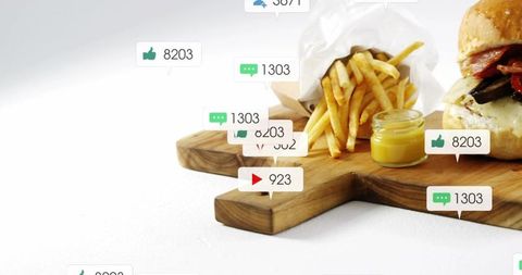 Burger and fries receiving social media engagement overlay on wooden serving board