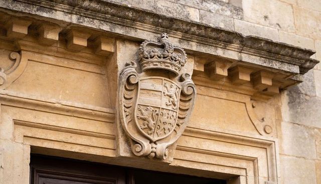 Stone heraldic coat of arms with crowned crest on historic sandstone doorway