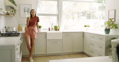 Stylish woman in minimalist kitchen enjoying smoothie