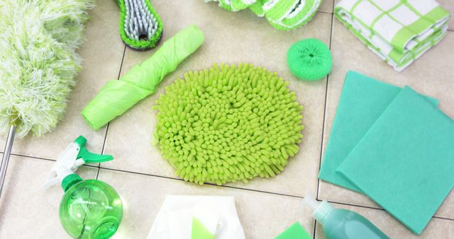 Various green cleaning supplies arranged on a tiled floor in an organized manner. Suitable for depicting spring cleaning, promoting eco-friendly cleaning products, and illustrating household chores. Ideal for use in home cleaning guides, eco-friendly product advertisements, and social media posts focused on cleanliness and organization.