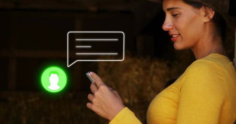 Woman checking messages in rustic barn with smartphone and neon chat notification
