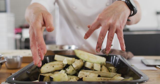 Close-up of chef seasoning sliced vegetables, suggesting professional cooking techniques. Ideal for use in culinary blogs, cooking tutorials, chef training content, or restaurant promotional materials.