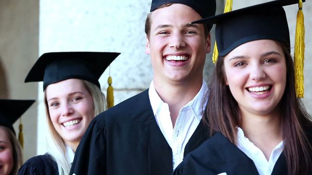 Graduates laughing and celebrating their achievements while wearing graduation caps and gowns. This video is ideal for use in educational websites, university promotional materials, graduation announcements, academic articles, and advertisements illustrating success and fulfillment in education.