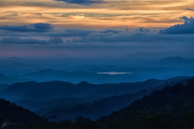Mountains layered under a vibrant twilight sky with a serene atmosphere, suitable for nature-themed backgrounds, travel blogs, calming prints, or promotional material emphasizing tranquility and beauty of natural landscapes.