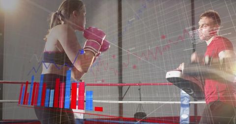 Female boxer training with coach using punch data overlays and analytics in boxing ring