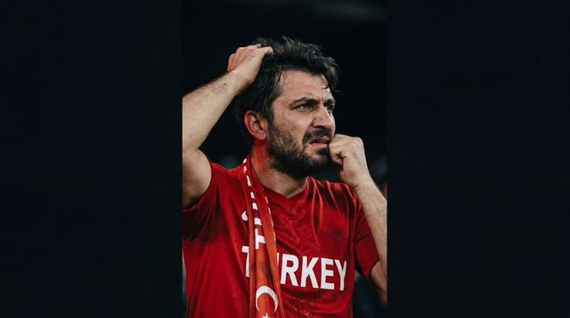 Emotional turkish football fan gripping head watching match in red turkey jersey