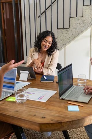 Diverse Coworkers Collaborating at Office Table with Laptops