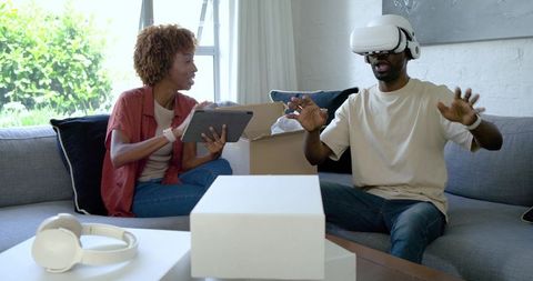 African American couple testing VR headset at home while unpacking and using tablet