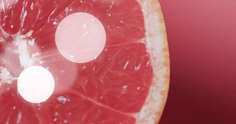 Displaying halved pink grapefruit with translucent pulp, juicy segments and soft bokeh
