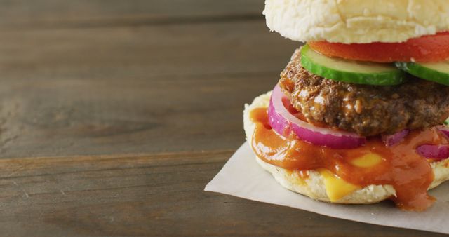 Close-up of a mouth-watering homemade hamburger with fresh ingredients, including a juicy patty, sliced cucumbers, tomatoes, red onion, melted cheese, and a savory sauce. Perfect for food blogs, restaurant menus, advertisements, social media posts, cooking websites, and nutritional content.