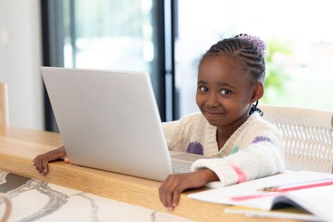 African American Girl Studying on Laptop at Home Kitchen Bar Smiling and Focused