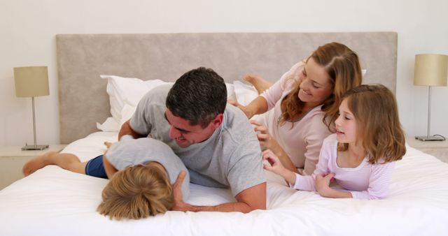 Happy family playing together on bed during morning - Download Free Stock Images Pikwizard.com