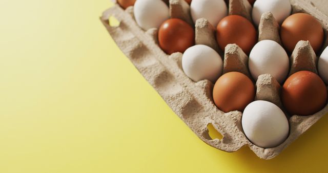 Image of eggs in packaging box on a yellow surface. seasonal easter traditional sweet treats.