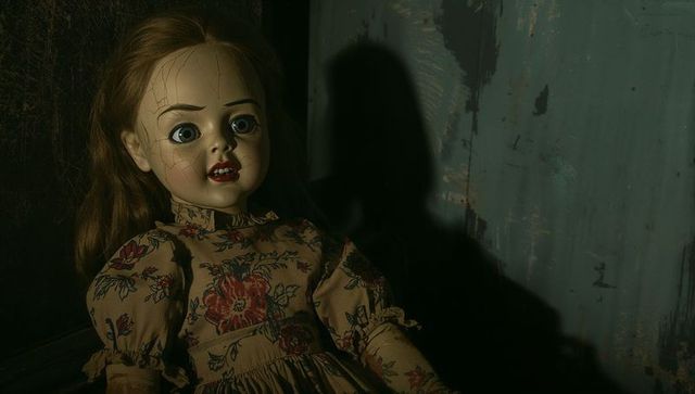 Vintage porcelain doll with cracked face on worn bench in dim light