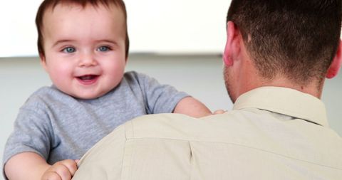 Father holding laughing baby at home before work