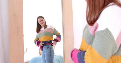 Woman Adjusting Clothes in Cozy Bedroom