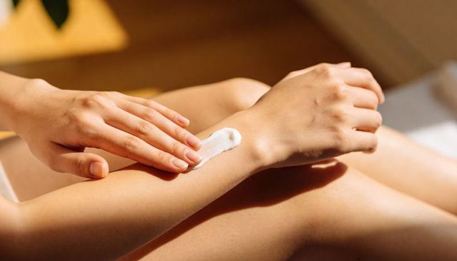 Applying moisturizer on inner forearm closeup, woman rubbing cream for dry skin hydration