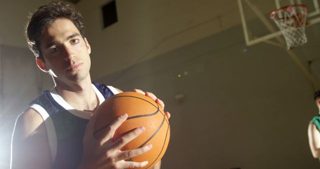 Young Basketball Player on Indoor Court Holding Ball, Focused Expression - Download Free Stock Images Pikwizard.com