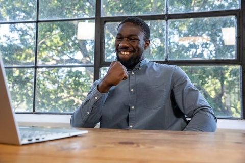 Excited Professional Celebrating Success at Work Desk