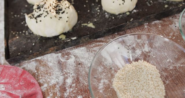 Preparing dough balls with black sesame seeds in a kitchen environment. Flour and a glass bowl with seeds seen in the foreground. Perfect for illustrating home baking activities, cooking tutorials, recipe blogs, or food preparation scenes.