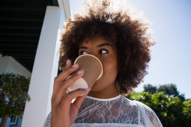 Young woman looking away while drinking coffee from disposable cup