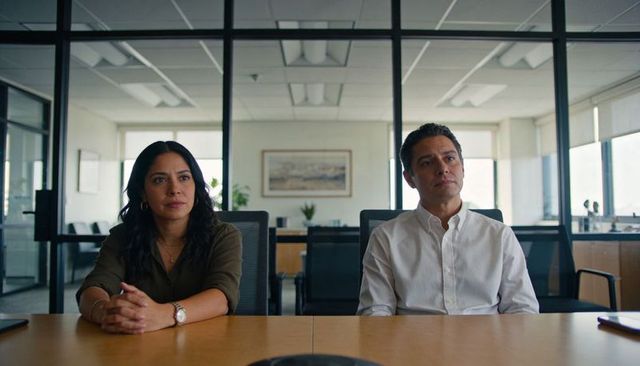 Business casual coworkers sitting across table in conference room with speakerphone