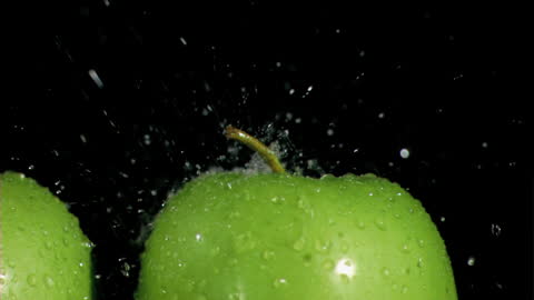Vibrant Green Apples Sprayed with Water in Slow Motion