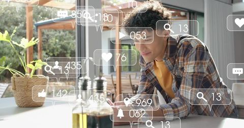 Young man leaning, scrolling smartphone at kitchen counter with social media notifications