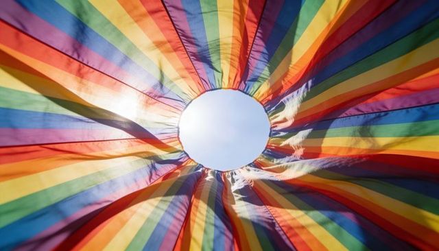 Rainbow canopy circle revealing blue sky and sun glare with frayed stitching