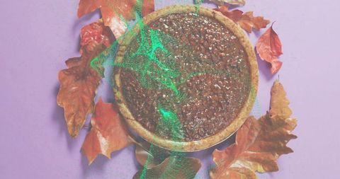 Displaying autumn pecan tart flatlay on pastel purple backdrop with dried leaves