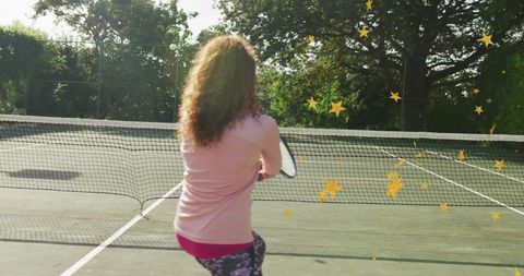 Woman playing tennis on sunlit outdoor court from behind with star graphic overlays