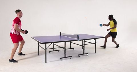 Diverse Athletes Engaged in Intense Table Tennis Match Indoors
