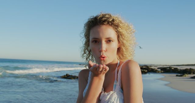 Young Woman Blowing Kiss on Sunny Beach at Sunset - Download Free Stock Images Pikwizard.com