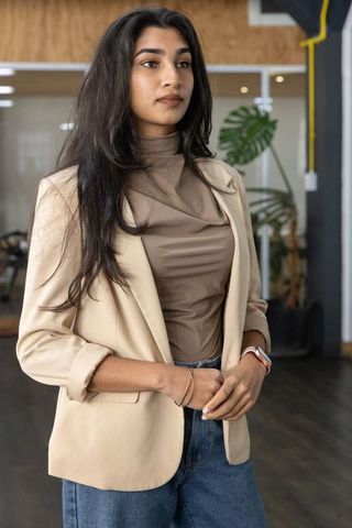 Confident indian businesswoman standing in modern coworking space wearing neutral blazer